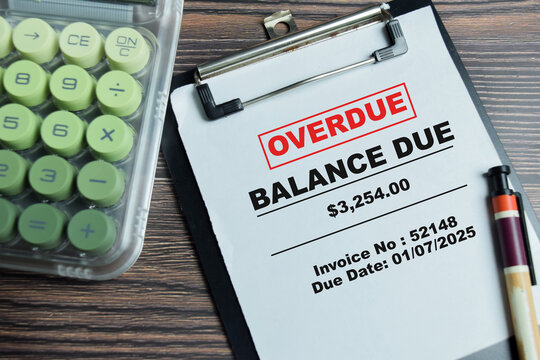 Concept of overdue invoice write on clipboard with red balance due stamp isolated on Wooden Table. For late payment accounting and debt management