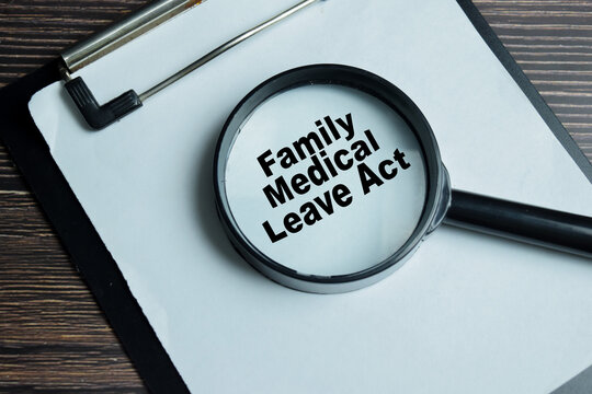 Concept of family medical leave act write on clipboard with compliance checklist isolated on Wooden Table. For employee rights workplace leave policy legal protection