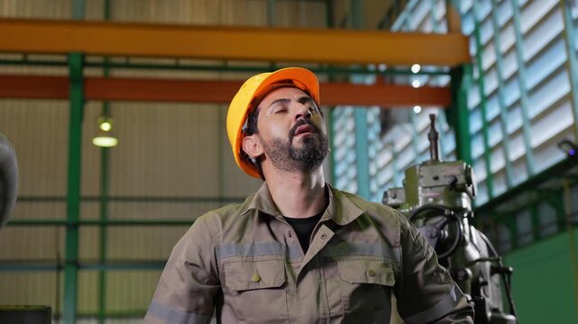 Tired industrial worker wiping sweat from forehead in manufacturing factory, Exhausted worker taking off hard hat and wiping sweat in industrial plant,Technician man resting after hard work