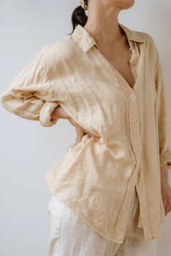 Detail View Of Elegant Unbuttoned Beige Linen Shirt On Woman Standing Against Neutral Background