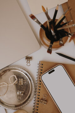Blank Mobile Phone Screen Mockup Laying On Kraft Paper Journal With Artist Supplies And Candle