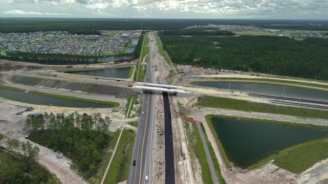 Aerial view of Silverleaf Parkway construction showing the bridge over the highway, surrounding retention ponds, and nearby residential development in St. Augustine, Florida, United States.