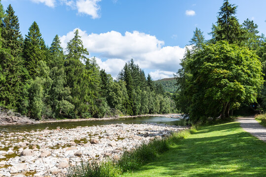 Scenic view of the River Dee near Balmoral Castle, flowing through a wooded Highland landscape with a peaceful riverside walking path in Scotland