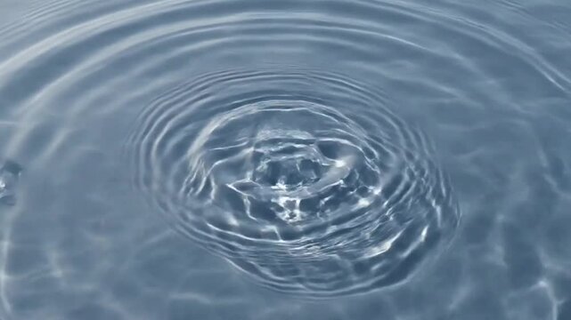 Water Ripples: Gentle water ripples spread outwards from the center of a clear blue liquid, creating intricate patterns of concentric waves on the surface.