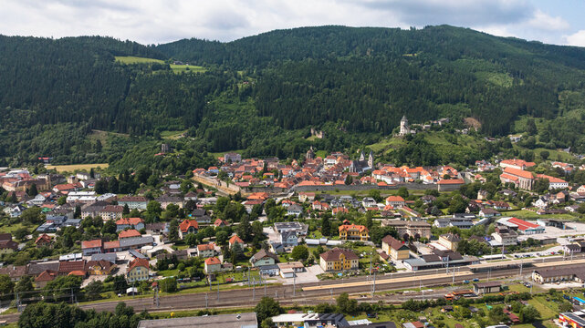 Summer drone footage showing medieval Friesach, old fortified walls, rooftops, towers, hills, serene atmosphere, warm daylight, gentle cinematic motion