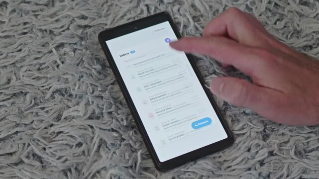 Person Endlessly Swiping Unread Business Messages in Smartphone Mail App Close Up