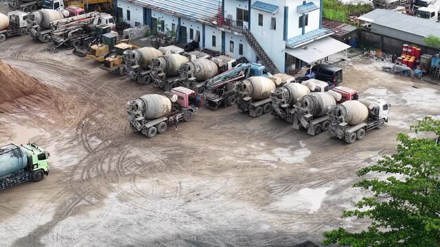 Aerial view of cement mixer trucks parked in a row and piles of raw materials for cement production