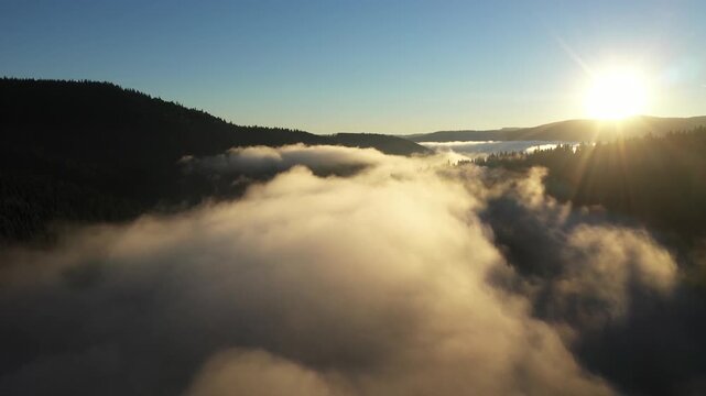 Slow motion aerial shot above the clouds and moving mist with sunrise in the morning time