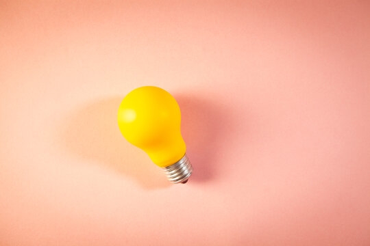 Yellow light bulb on a pink background. Minimalism style.
