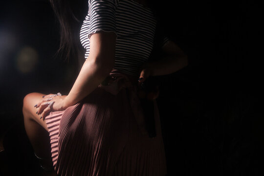 Young beautiful woman in a dress posing in a dark room.