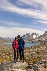Fototapeta premium Beautiful european family with children and pet dog, hiking Kyrkja mountain on a beautiful sunny summer day, sunset, snow, lakes, valley