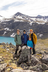 Naklejka premium Beautiful european family with children and pet dog, hiking Kyrkja mountain on a beautiful sunny summer day, sunset, snow, lakes, valley