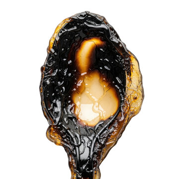 Close-up of a Spoon Filled with Thick Dark Cannabis Resin Extract or Molasses Isolated on White Background