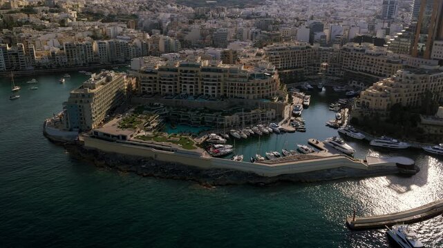 Captivating aerial footage showcases the beautiful Portomaso Marina in St. Julian's, Malta, filled with yachts and surrounded by stunning coastal architecture.