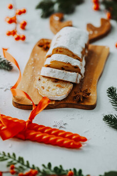 Sliced fruitcake dusted with sugar on a wooden board with festive decorations and red candles