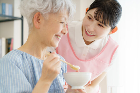 お粥を食べる日本人シニア女性と若い日本人看護師