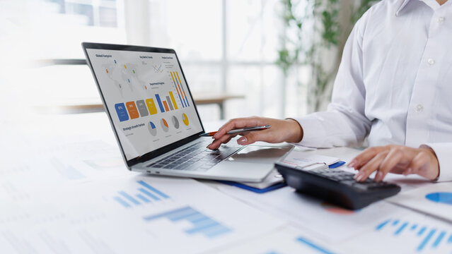 Confident business point to graphs and charts to analyze market data, balance sheet, account, net profit to plan new sales strategies to increase production capacity.