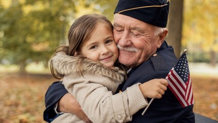 Fototapeta premium elderly military veteran grandfather hugging his young granddaughter holding a small american flag in an autumn park
