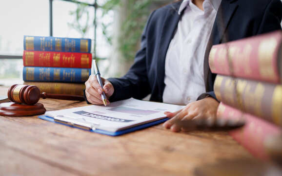 justice and law concept. Female lawyer working in office. Legal law, advice and justice concept.Lawyer or Judge Signing Contract Legal Document with Gavel and Law Books on Desk