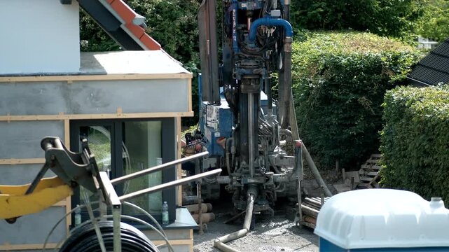 Germany, Ludinghausen, June 15 2025. Detailed view of a hydraulic drilling rig with pipes and hoses during deep ground excavation next to a house.