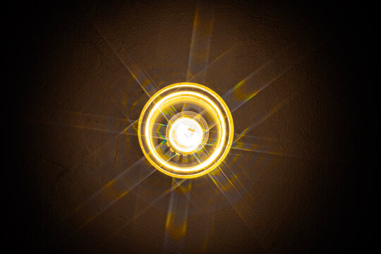 a round downlight fixture emitting a bright, warm light with visible radial diffraction spikes or lens flares