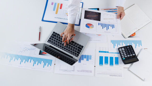 Confident business people point to graphs and charts to analyze market data, balance sheet, account, net profit to plan new sales strategies to increase production capacity.