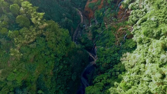 Aerial view of Tetes Cave and Waterfall surrounded by lush tropical forest and river in Kecamatan Pronojiwo, Jawa Timur, Indonesia.