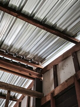 Rustic Wooden Barn Interior Framing with Corrugated Metal Roof Structure and Natural Ceiling Sunlight