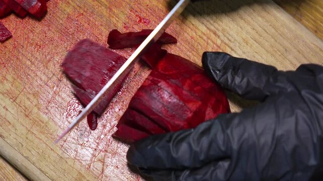 Fresh beet slicing, chef cutting raw beetroot into slices on wooden board. Overhead static shot.