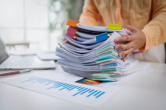 Businesswoman hands working in Stacks of paper files for searching and checking unfinished document achieves on folders papers at busy work desk office