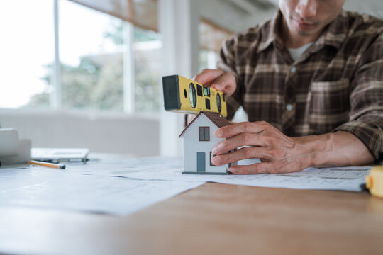 Architect working on house construction plans with blueprints, color samples, measuring tools and architectural drawings on a wooden desk.