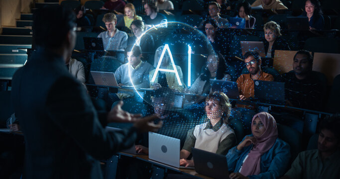 Rear View of a Professor Gesturing Toward a Glowing Ai Hologram Sphere While Lecturing Attentive Multiethnic University Students Working on Laptops in a Dark Tiered Auditorium Classroom.