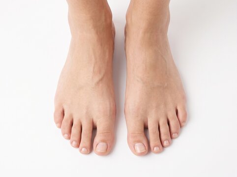 Young woman's beautiful bare feet and toes top view. Closeup isolated on white background.