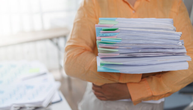 Business woman Auditor Holding Large Stack of Financial Documents working with financial documents Files in the office