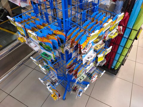 Malang, Indonesia - July 18, 2026: A blue wire retail display stand filled with packaged Hot Wheels die-cast toy cars hanging on metal hooks.