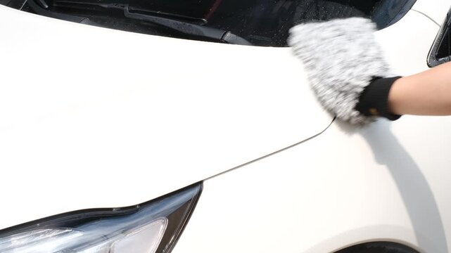 A man's hand washes a car with a rag close-up.