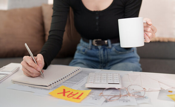 Woman calculating tax with calculator notebook and receipts at home desk