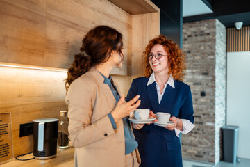 Fototapeta premium Businesswomen talking during coffee break in office kitchen