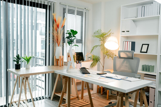 Spacious contemporary home office designed for productivity and comfort. Featuring an l-shaped wooden desk with a computer. Laptop. Documents. And an ergonomic chair
