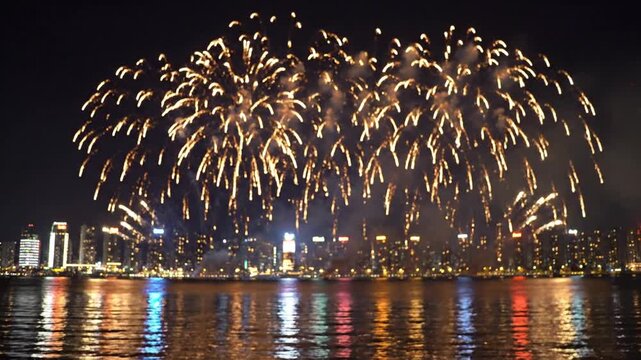 Gold fireworks exploding over city skyline at night with reflections