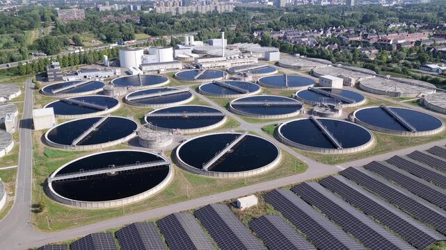 Aerial view of circular water treatment tanks and solar panel arrays at the industrial facility in Den Hoorn, South Holland, Netherlands.