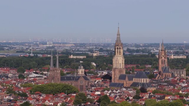 Aerial view of the historic city of Delft featuring the Nieuwe Kerk and Oude Kerk surrounded by traditional Dutch rooftops and lush greenery in Delft, South Holland, Netherlands.