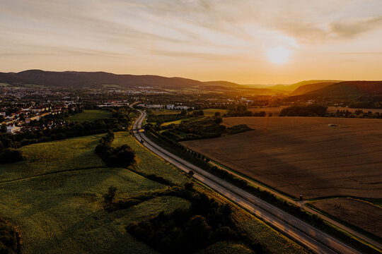 Golden hour aerial landscape with winding highway and sunflower fields near Saalfeld