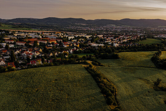 Aerial view of a German town named Gorndorf nestled behind sunflower fields at sunset