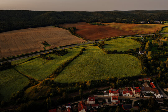 Aerial view of a vast sunflower field and rural highway at sunset near Saalfeld