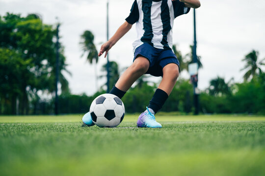 Kid boy leg kicking soccer ball on green grass field action. conceptual metaphor for youth sports training team competition fitness health wellness and active lifestyle