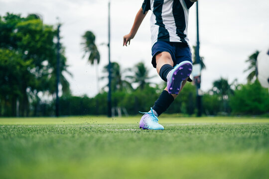 Kid boy leg kicking soccer ball on green grass field action. conceptual metaphor for youth sports training team competition fitness health wellness and active lifestyle