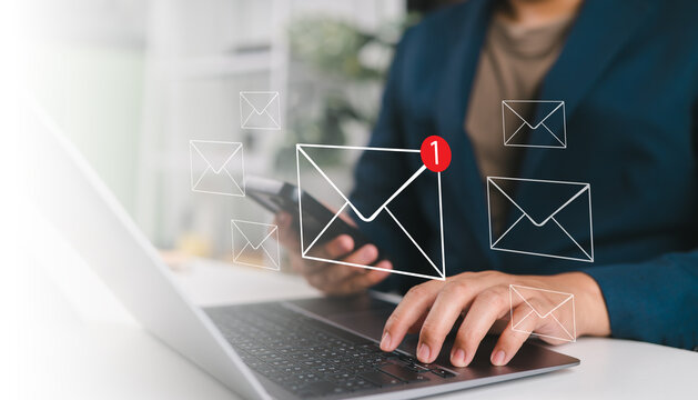 Business professional working on laptop and smartphone with virtual email notification icons, concept of inbox email marketing, online communication, digital workflow and modern business technology.