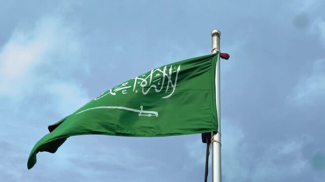 Saudi Arabia Flag Waving on Flagpole Against Clear Blue Sky