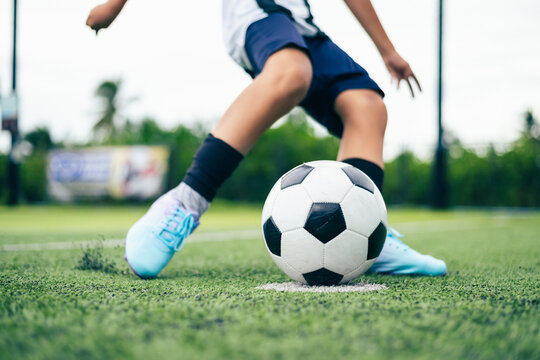 Kid boy leg kicking soccer ball on green grass field action. conceptual metaphor for youth sports training team competition fitness health wellness and active lifestyle